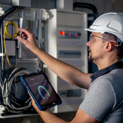 Man, an electrical technician working in a switchboard with fuses. Installation and connection of electrical equipment.